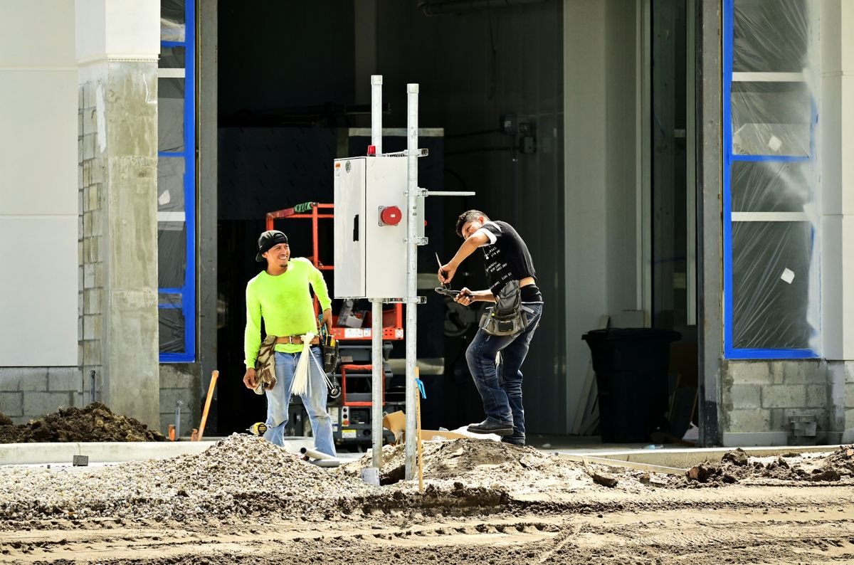 Dos trabajadores con equipo de seguridad instalando un cuadro eléctrico
